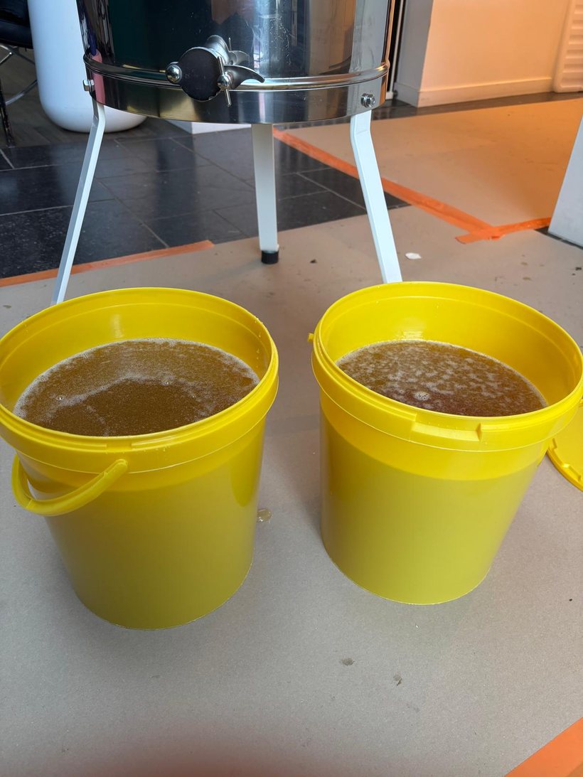 Twee emmers met versgeslingerde honing bij de slinger